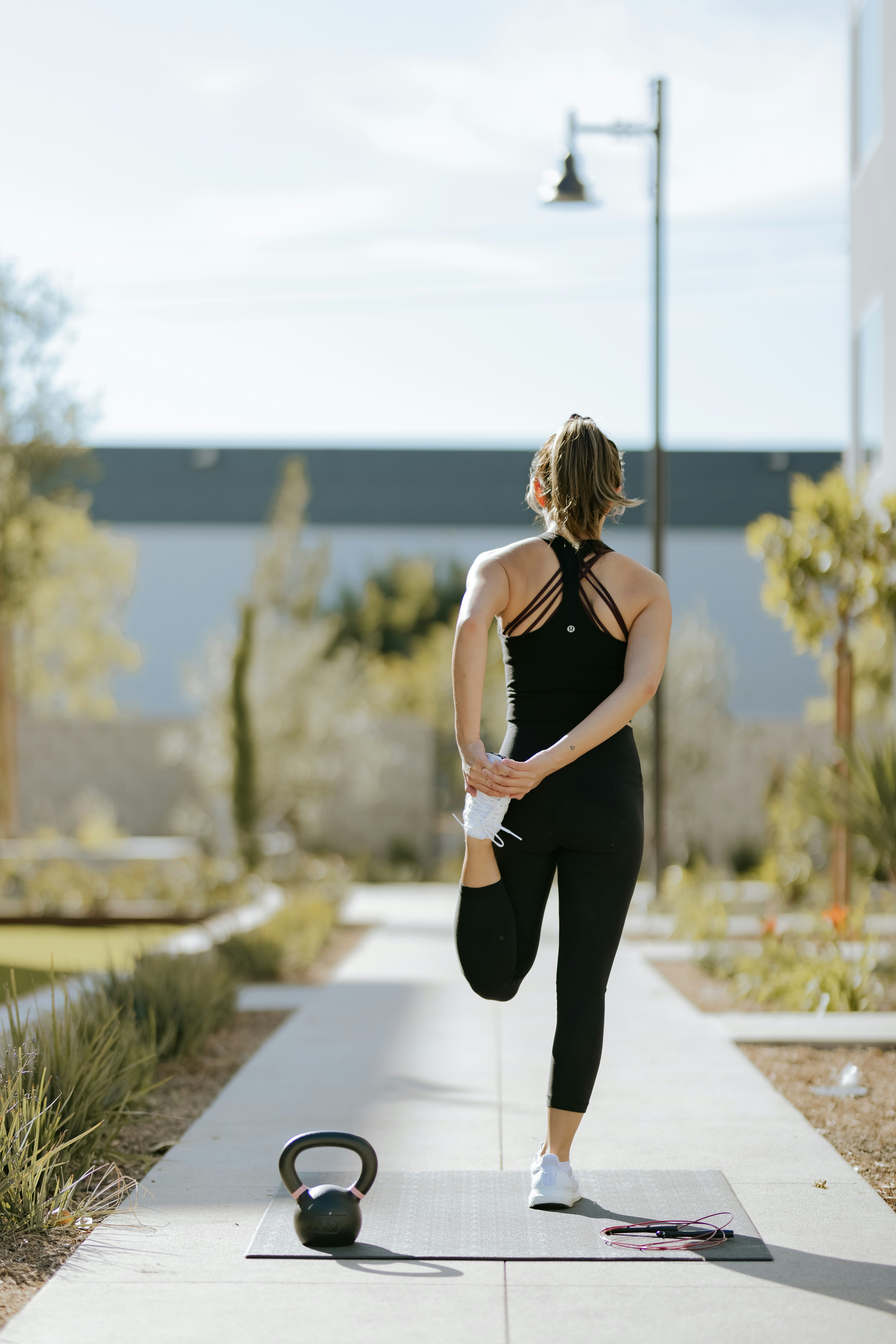 Movement — woman stretching outdoors with kettlebell and jump rope